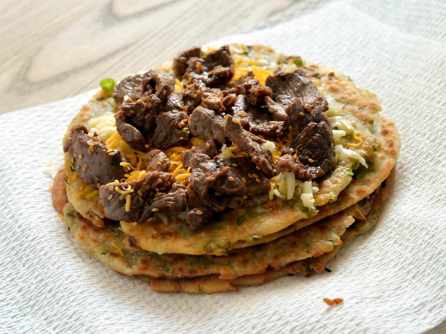 Scallion pancakes are topped with the bulgogi and cheese.