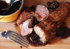 Sliced pan-roasted pork tenderloin next to bowl of bourbon fig glaze.