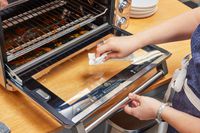 A person cleaning the Breville the Smart Oven Air Fryer with a paper towel