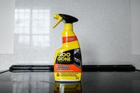 A bottle of Goo Gone Kitchen Degreaser placed on a stovetop in front of a tiled backsplash
