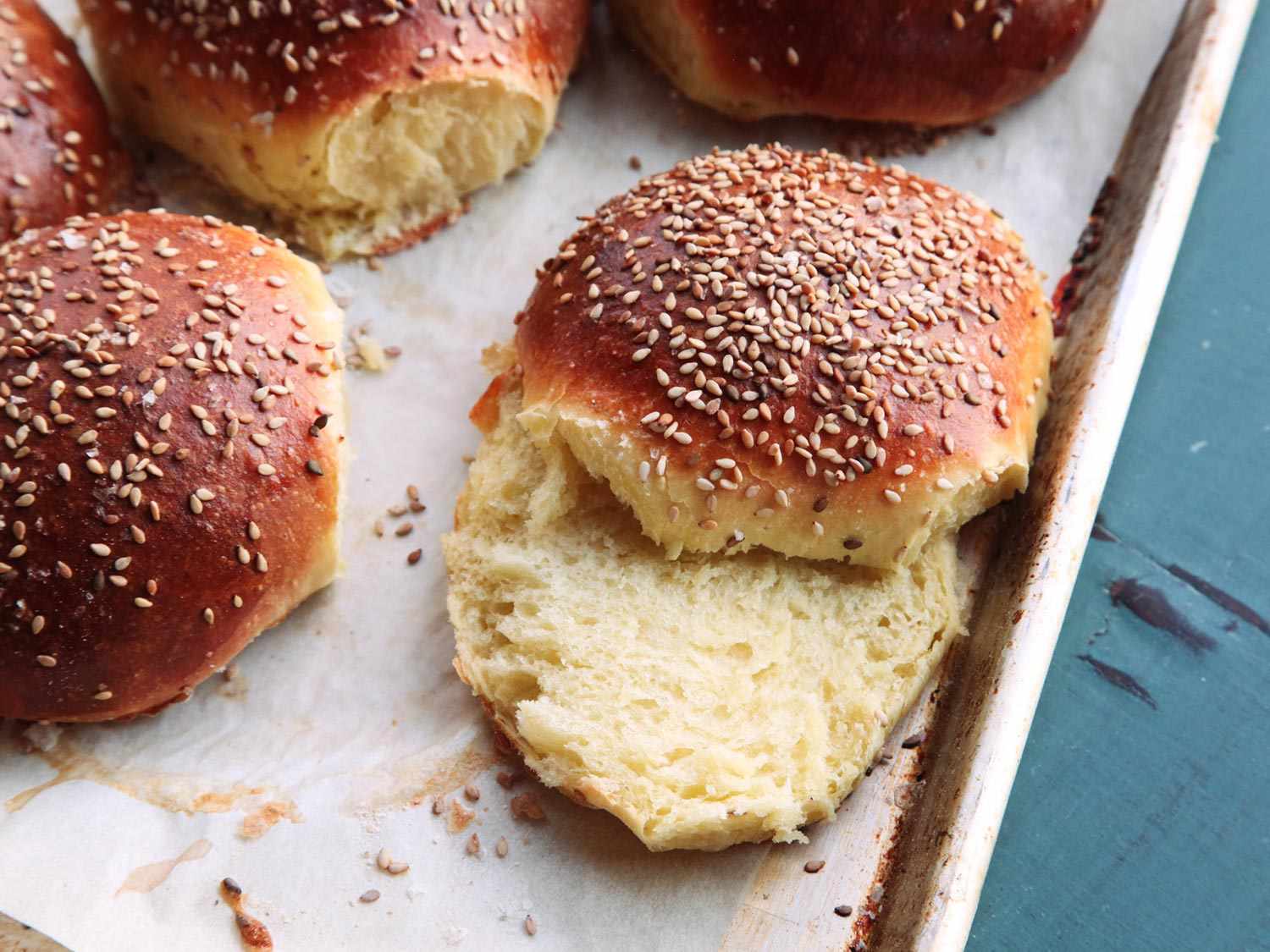 A tray of cooked cemita buns, golden-brown and topped with sesame seeds.