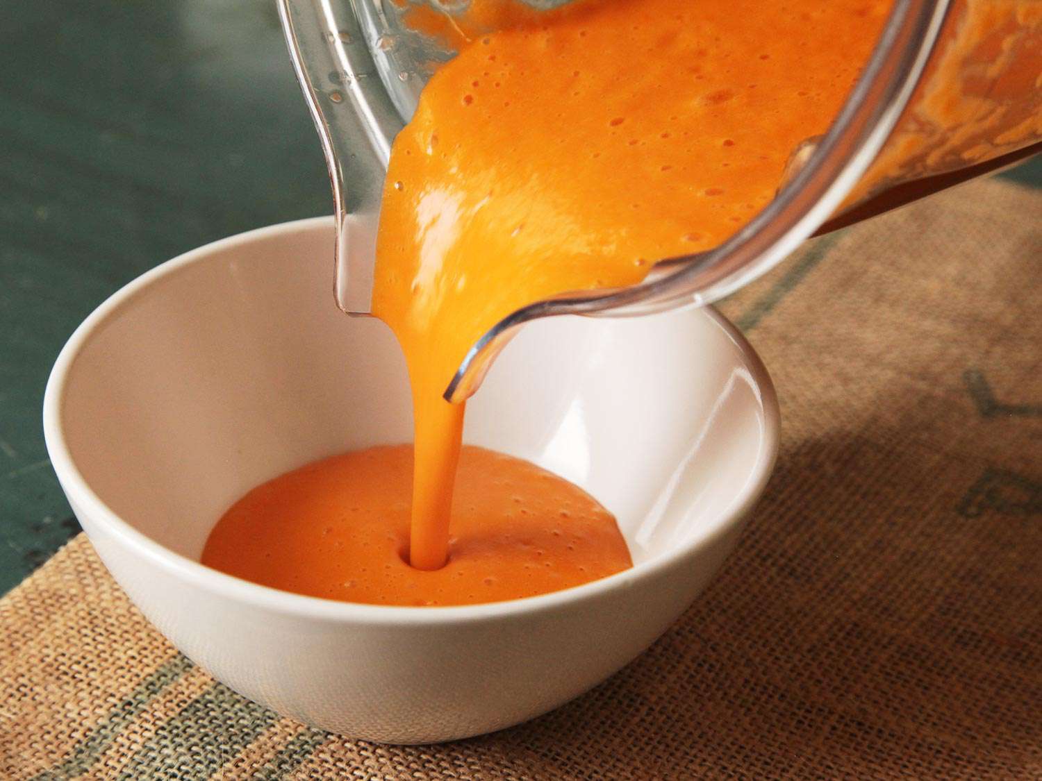 Pouring blender tomato soup into a bowl