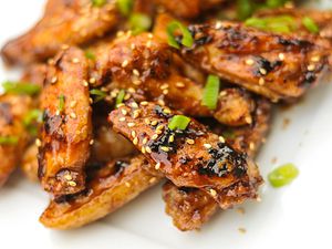 hoisin chicken wings garnished with sesame seeds and chopped scallion green