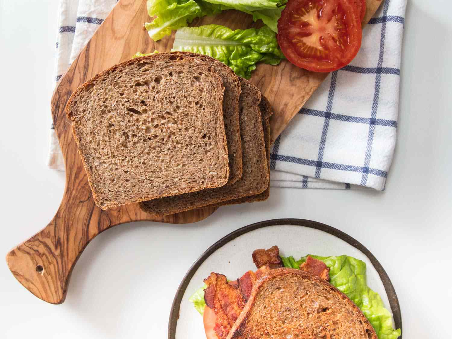 Overhead shot of sliced multigrain bread, tomato slice, and lettuce for BLT.