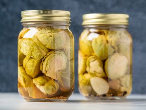 Two glass jars holding pickled brussels sprouts.