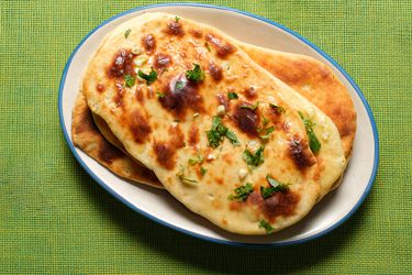 Garlic Naan on a white plate on a lime green tablecloth