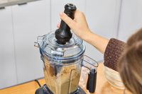 A person using an accessory on the Vitamix Ascent X5 Blender