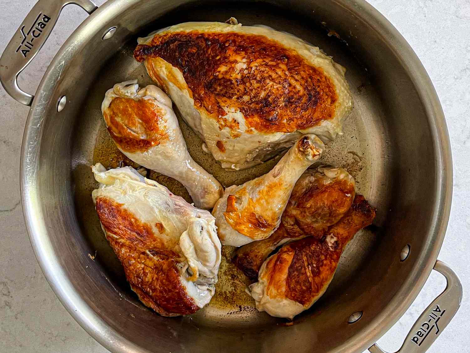 Chicken pieces searing in a stock pot.