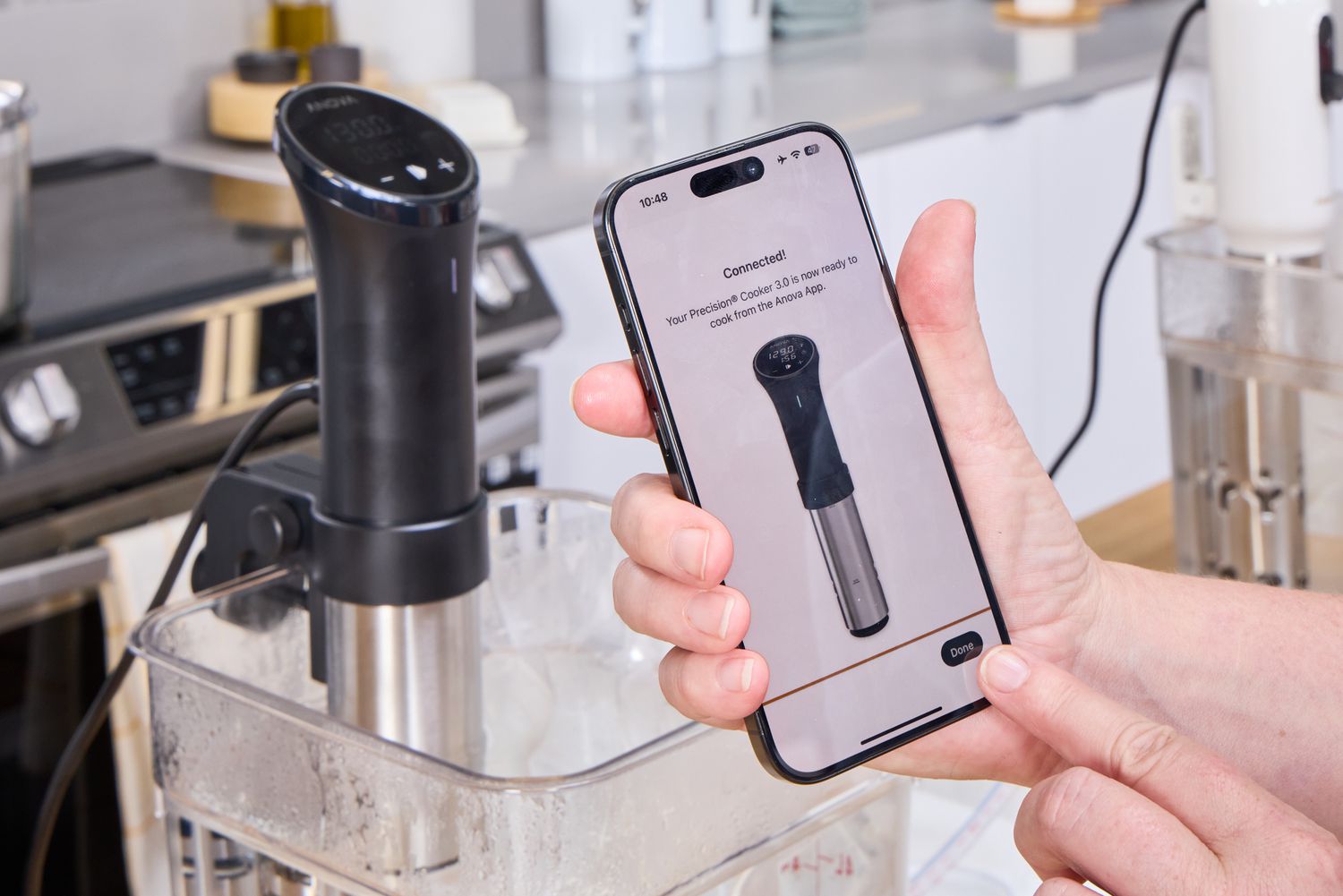 A person controls the Anova Precision Cooker 3.0 using their smartphone