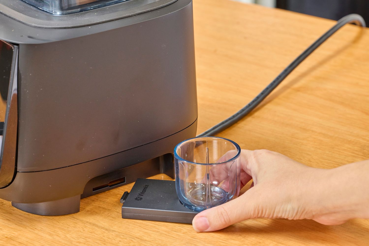 A hand holding a part to the Vitamix Ascent X2