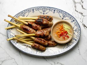 Platter with pile of nem lui skewers next to dipping sauce ramekin