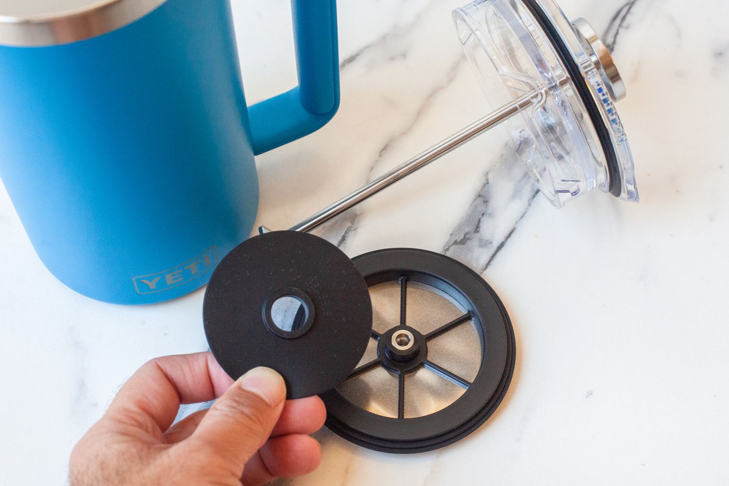 A hand picking up pieces of the Yeti French Press