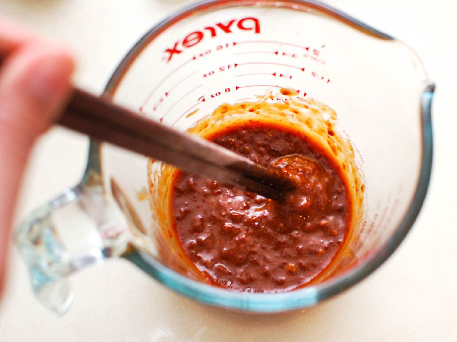 Mixing the marinade for the grilled tofu in a measuring cup. The marinate consists of chipotle peppers and their sauce, miso, vegetable oil, and brown sugar.