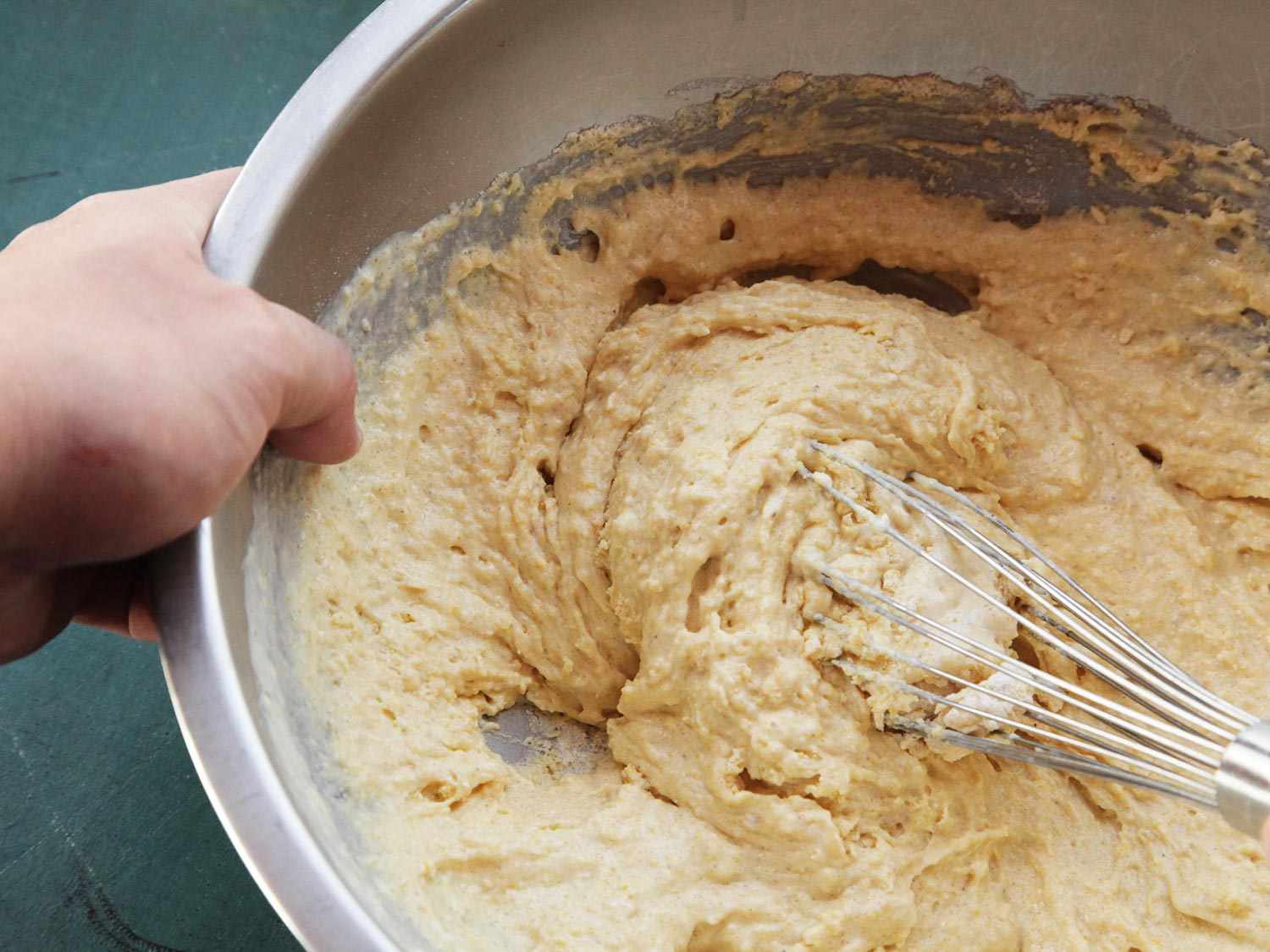 Whisk stirring cornbread batter in metal bowl