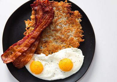 Crispy shredded hash browns with sunny-side up eggs and bacon