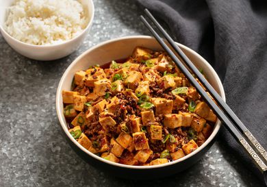 A bowl of spicy mapo tofu with a side of rice.