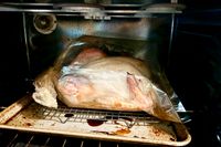 A turkey roasting in a bag on a tray in an oven