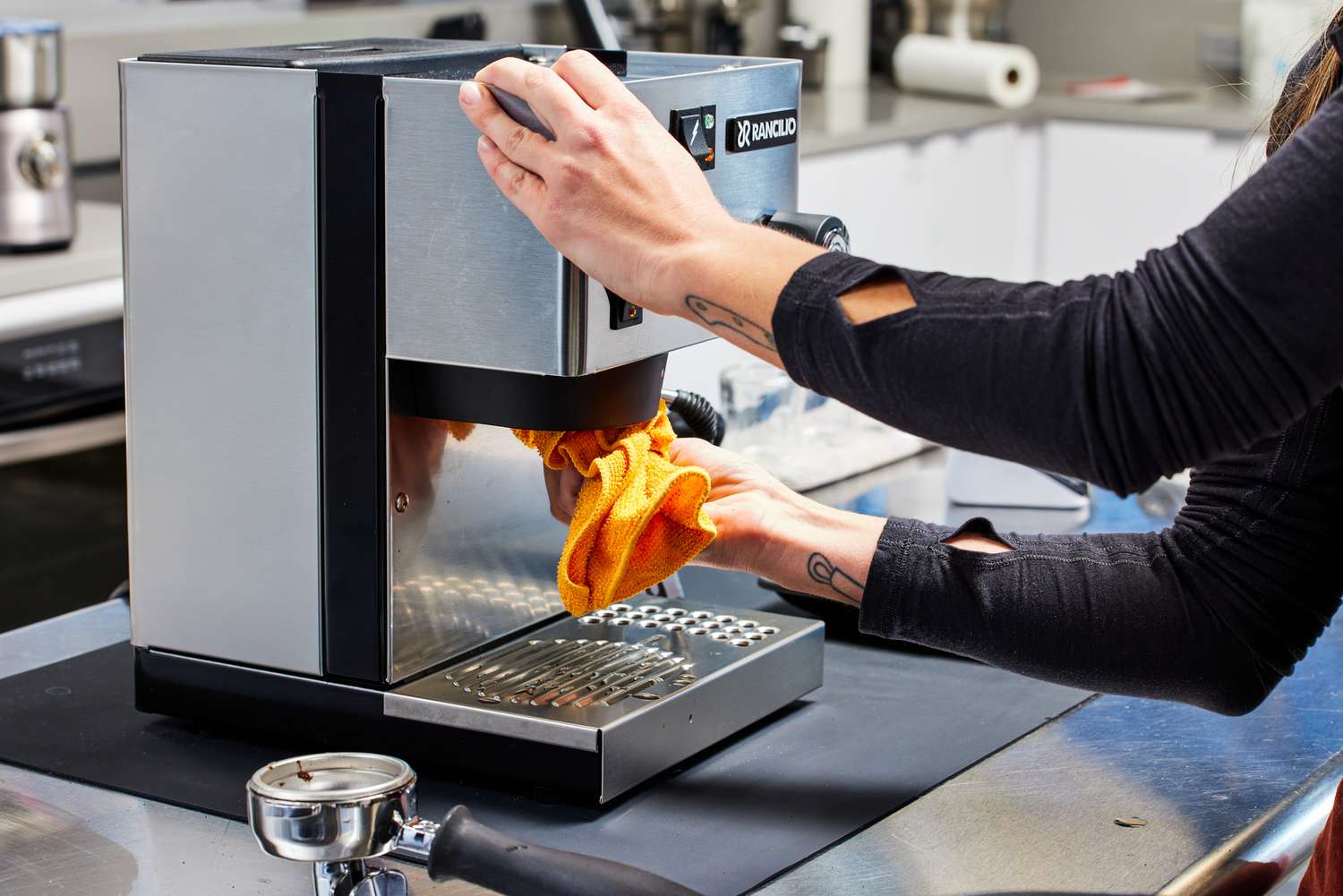 A person cleaning the Rancilio Silvia Espresso Machine with a yellow cloth towel