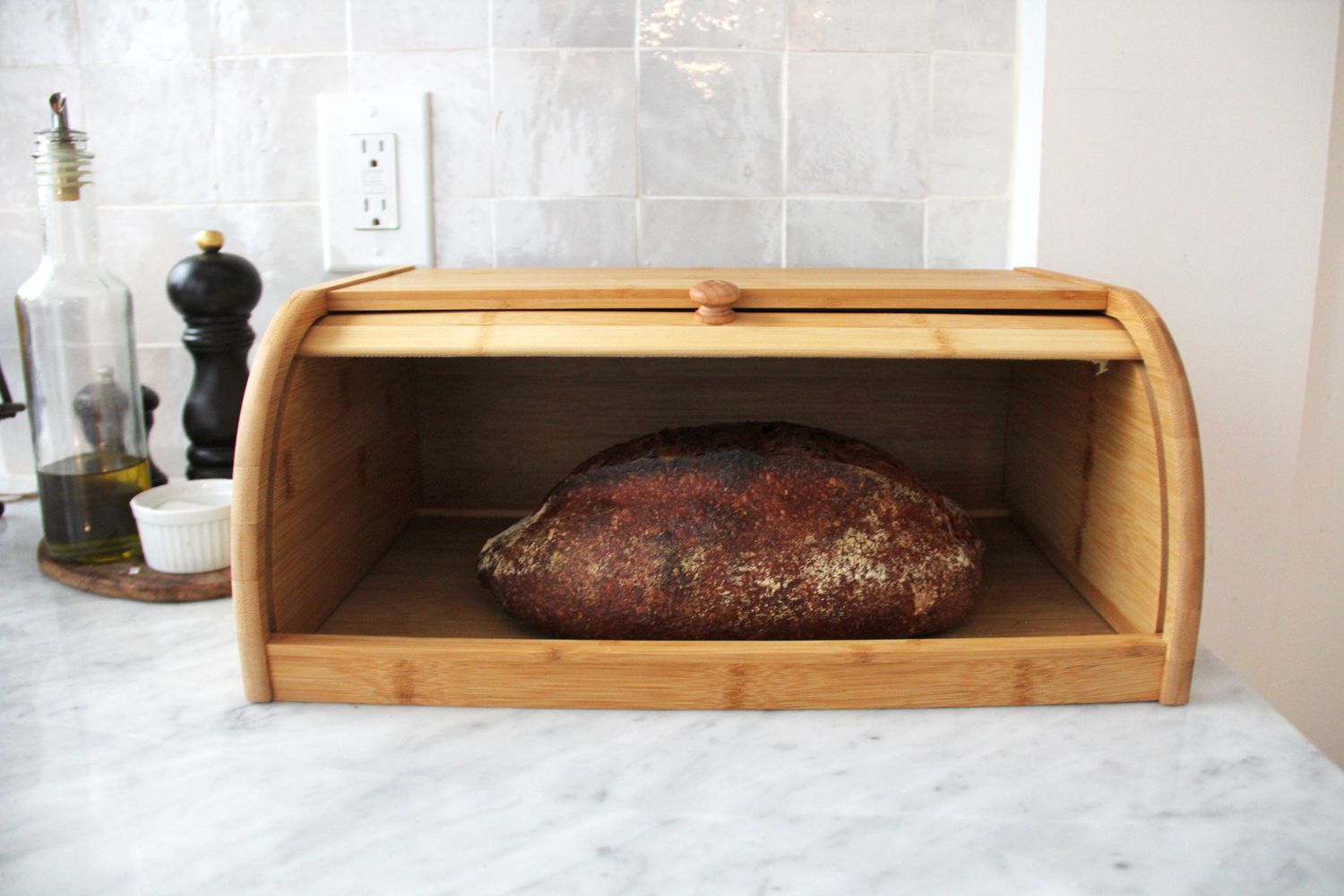 A loaf of bread in a wooden bread box.