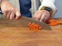 a person using the Tojiro santoku to dice carrots