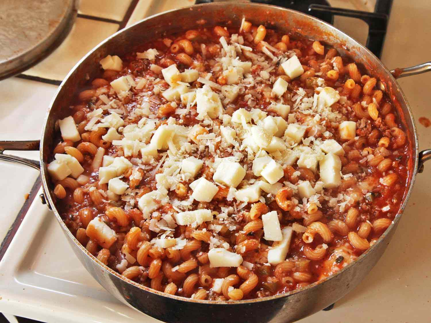 Cubed mozzarella and grated Parmesan are scattered over the surface of the casserole.