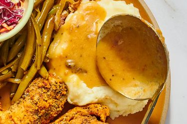 A plate featuring green beans mashed potatoes with gravy fried chicken and a side of coleslaw