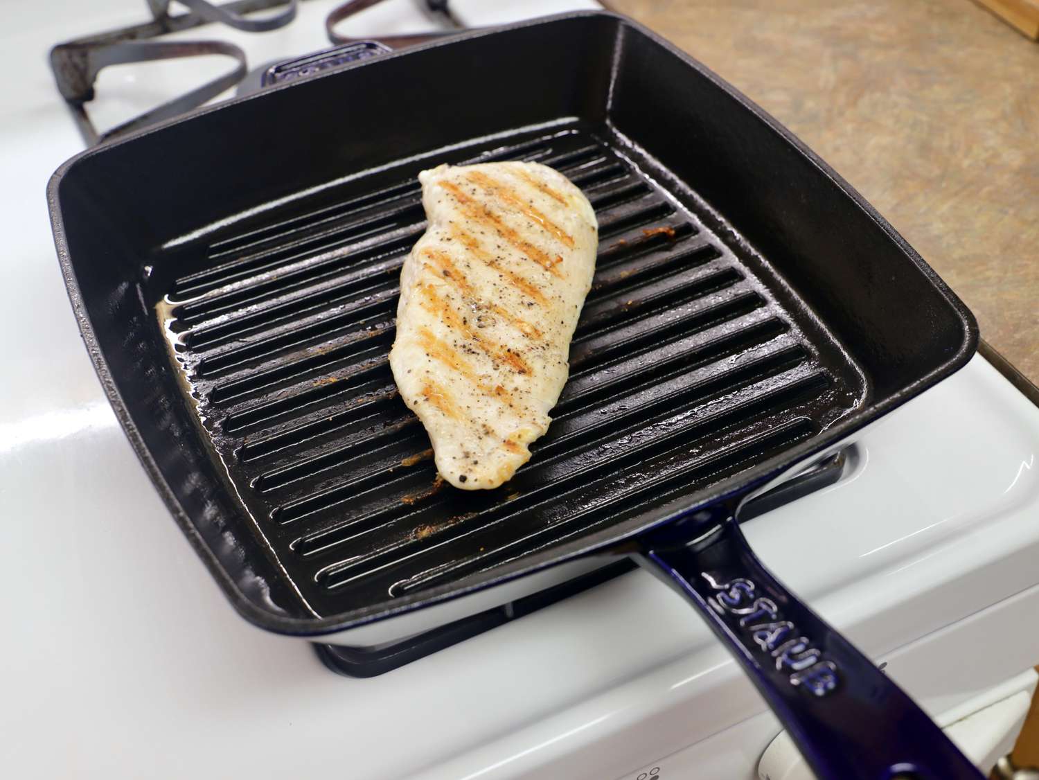 A pork chop cooking on the Staub Enameled Cast Iron Grill Pan
