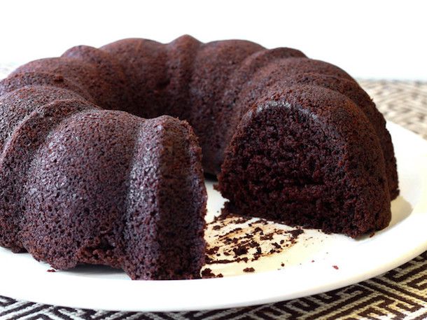 Gluten free chocolate bundt cake on a platter, with one slice missing