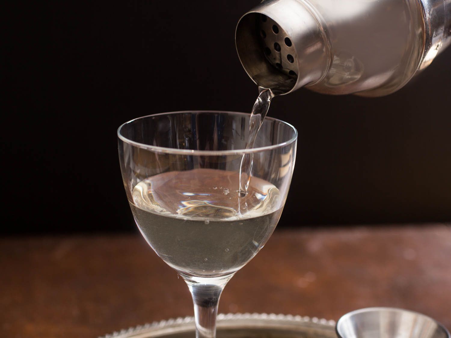 Closeup of a sherry martini being poured from a cobbler style shaker.