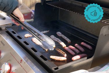 a person flipping sausages on the weber griddle insert