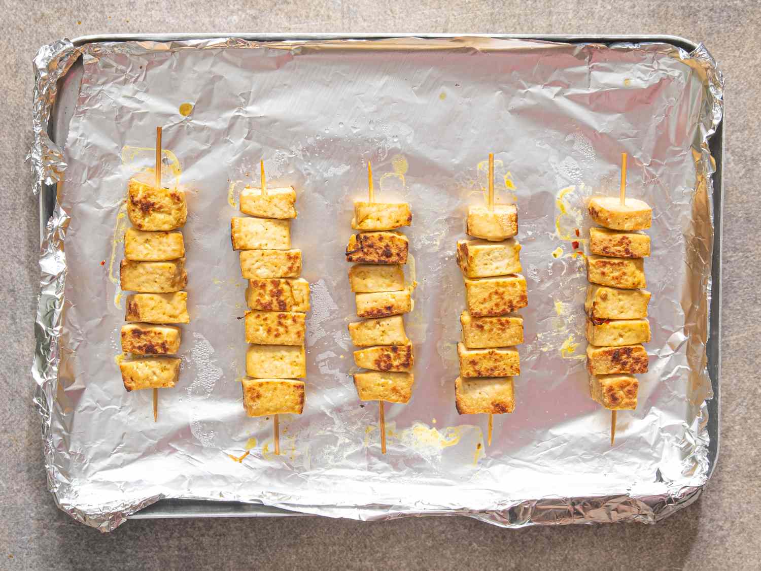 Tofu skewers arranged on a foillined baking sheet