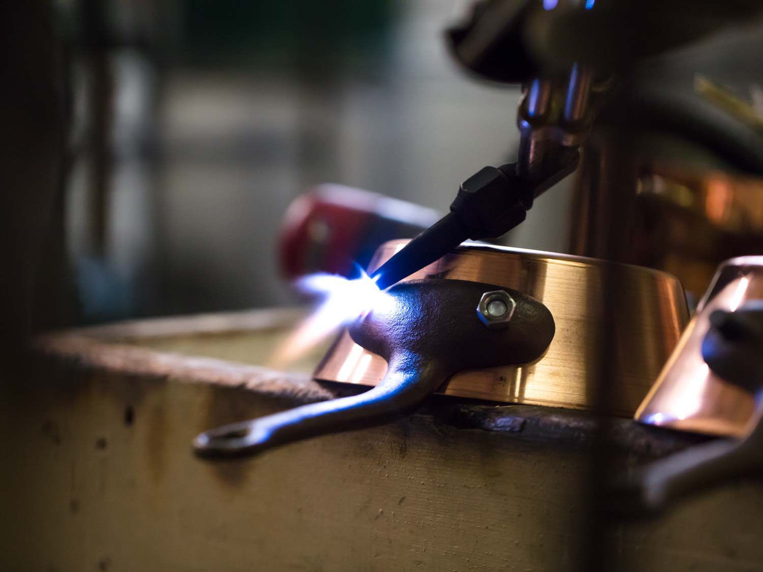 Rivets being heated on a handle of a handmade copper pot.