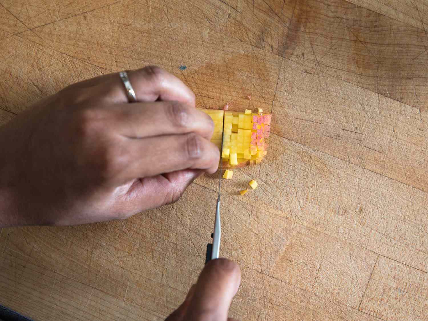 Finely dicing an apple with a utility knife on a wooden cutting board