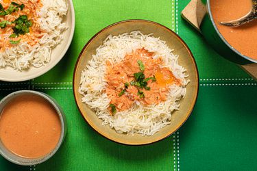 3 bowls of rice and Tomato Coconut soup, dutch oven on the side, and green tabletop.