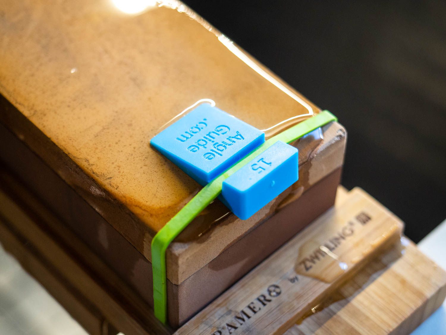 A small plastic 15-degree angle guide is rubber banded to the end of a whetstone