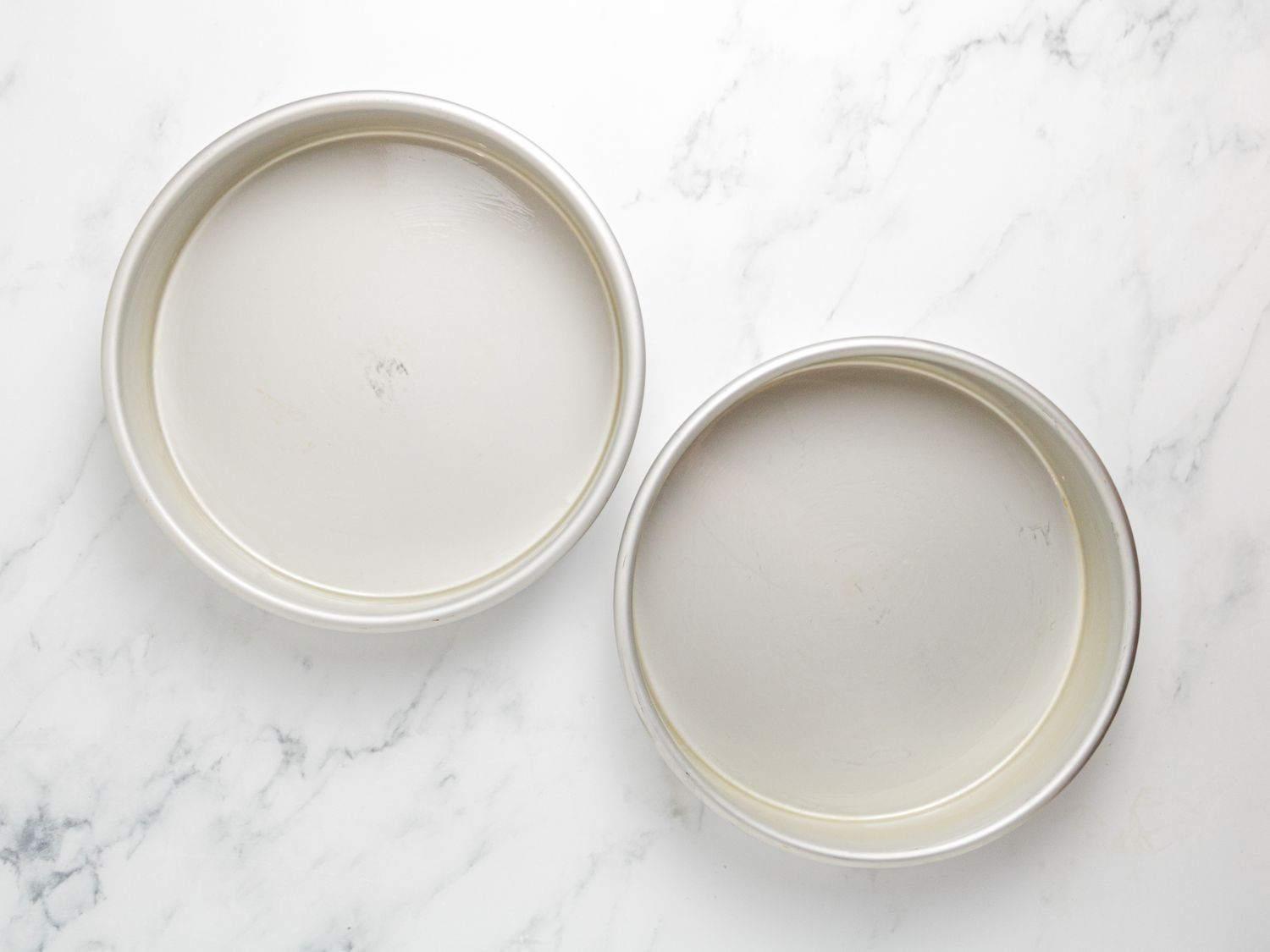 Two round baking pans on a marble surface