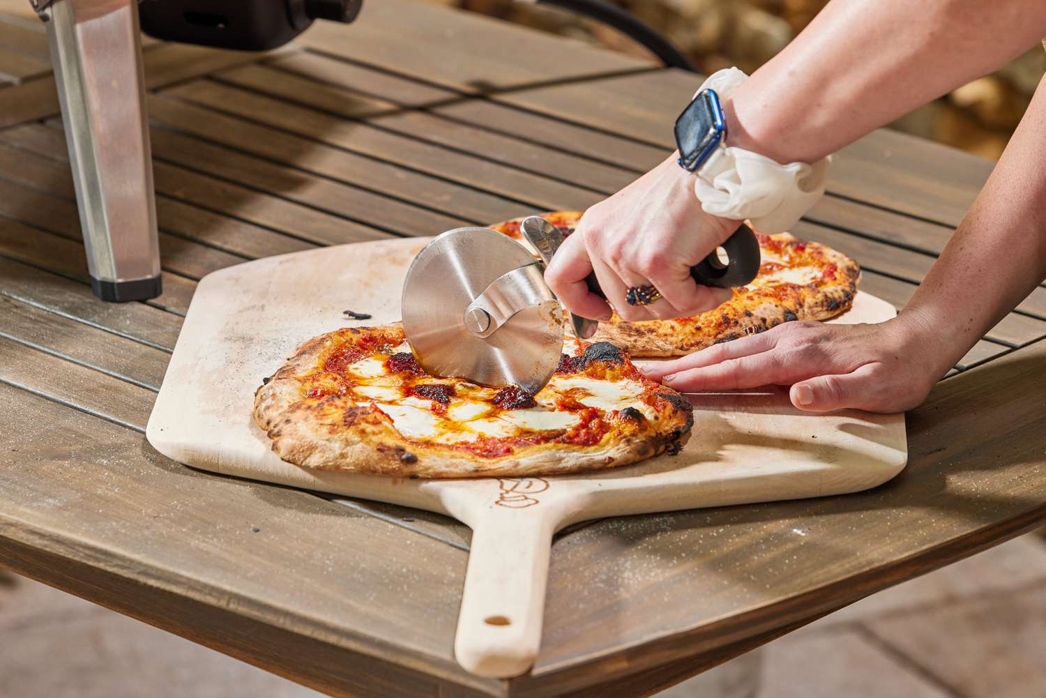 A person cutting a pie made in the Ooni Koda 16 Gas Pizza Oven