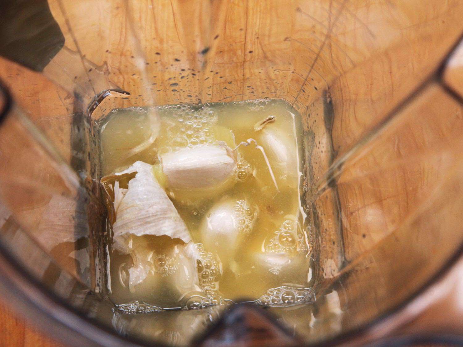 Overhead shot of whole garlic and lemon juice in a blender