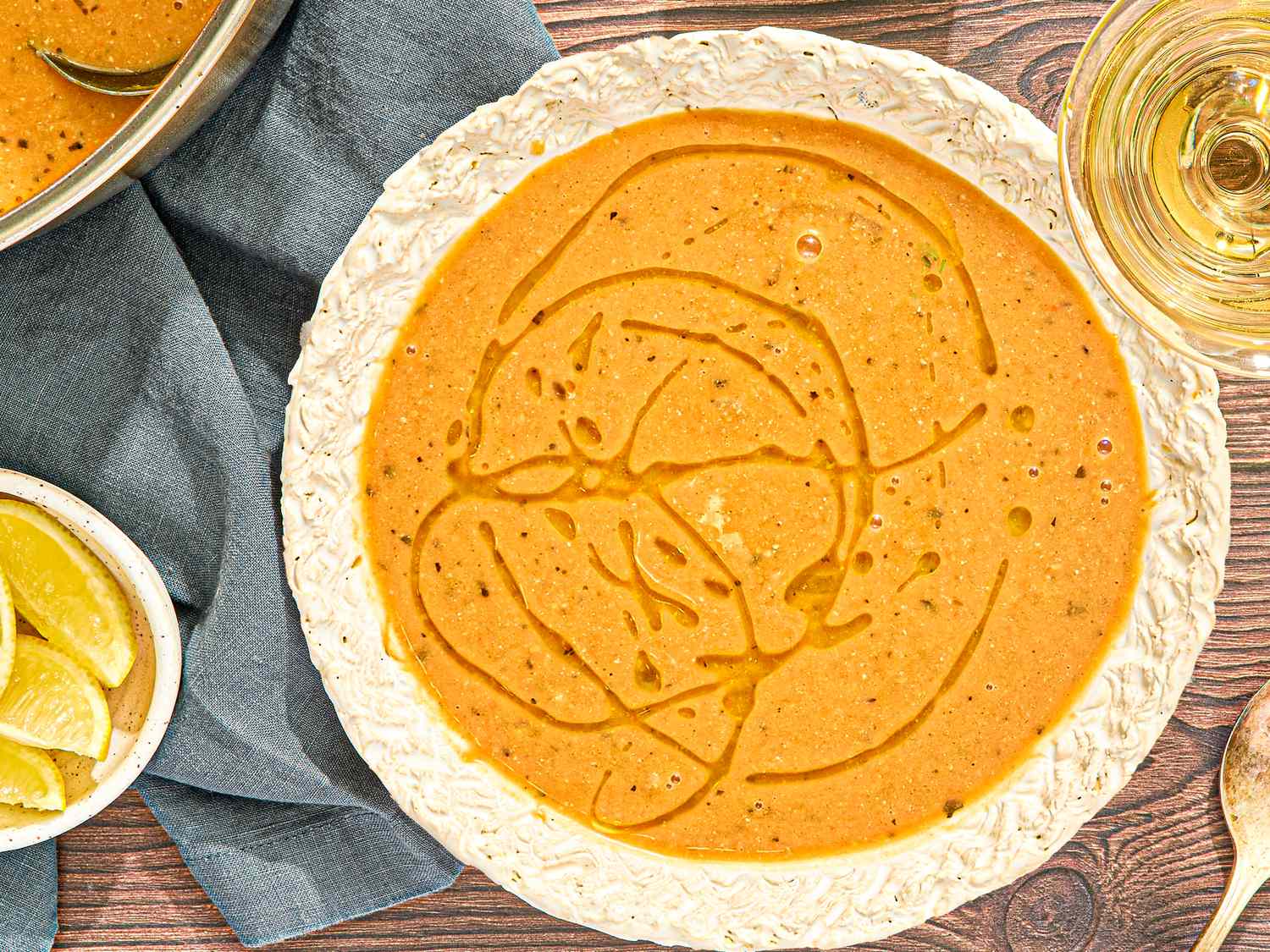A serving of chickpea stew garnished with olive oil drizzles on a wooden table with slices of lemon nearby