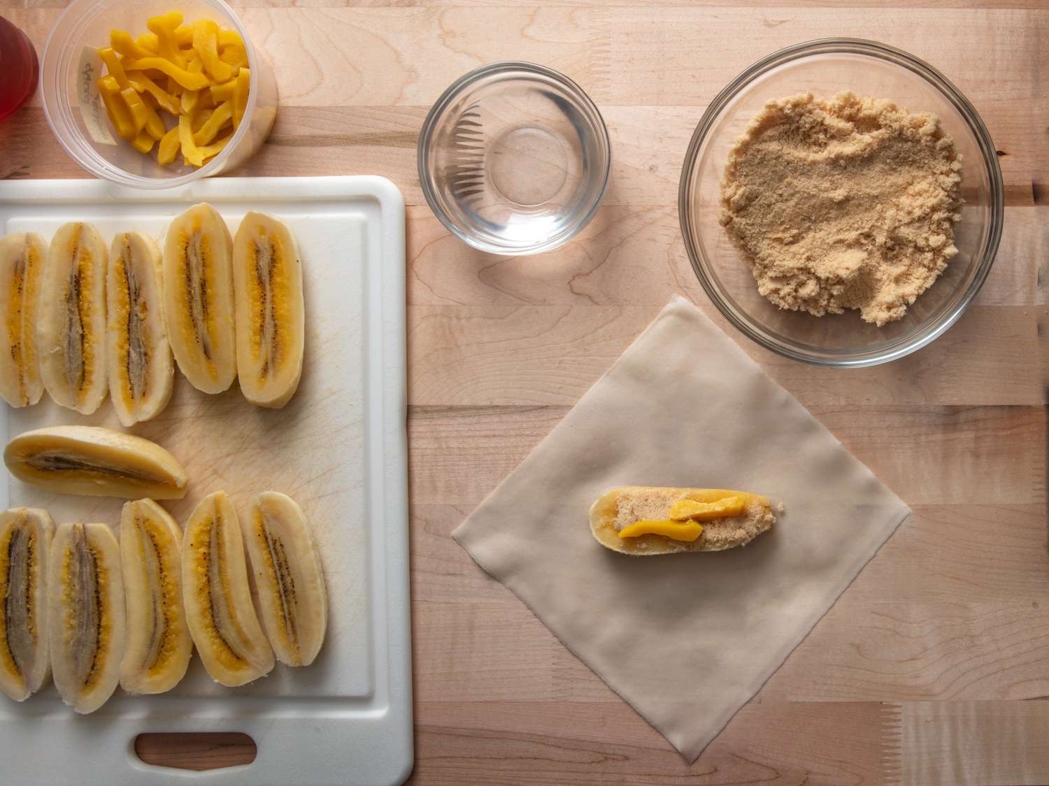 a slice of saba banana rolled in brown sugar and topped with 2 pieces of jackfruit in the center of a spring roll wrapper