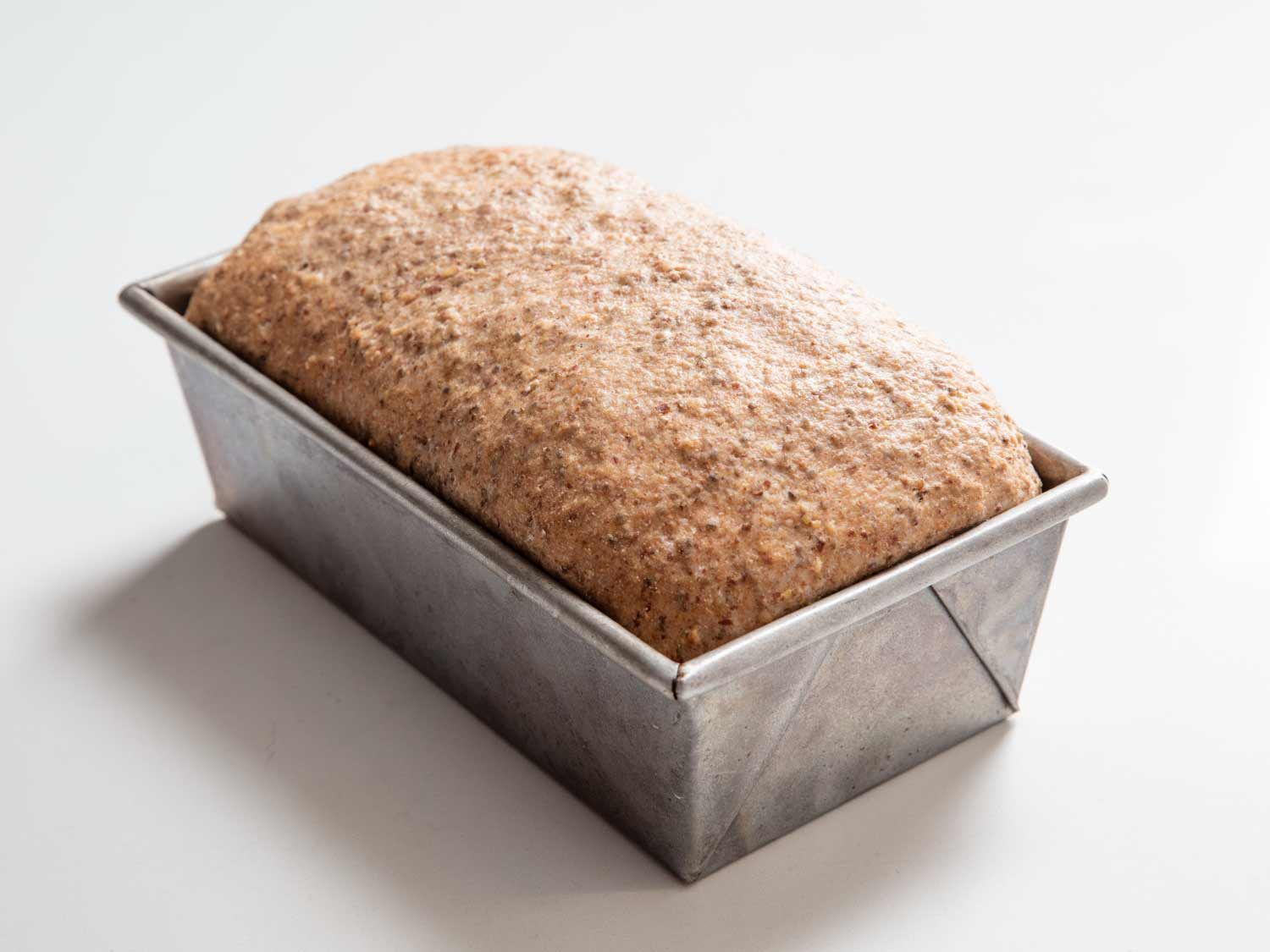 Proofed multigrain bread in a loaf pan, ready to bake.