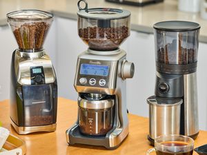 Three burr coffee grinders on a kitchen countertop.
