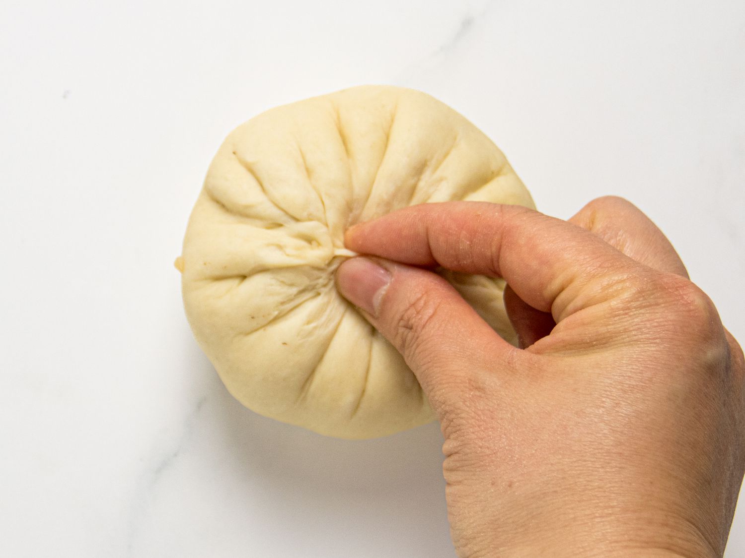 Pinching bun together at the center with fingers