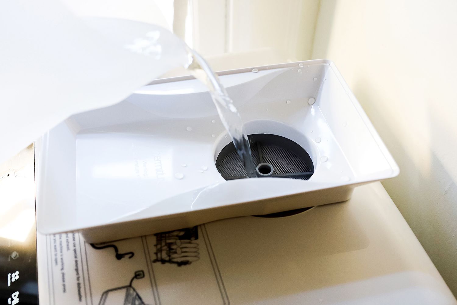 Water being added to the water reservoir of a countertop dishwasher.