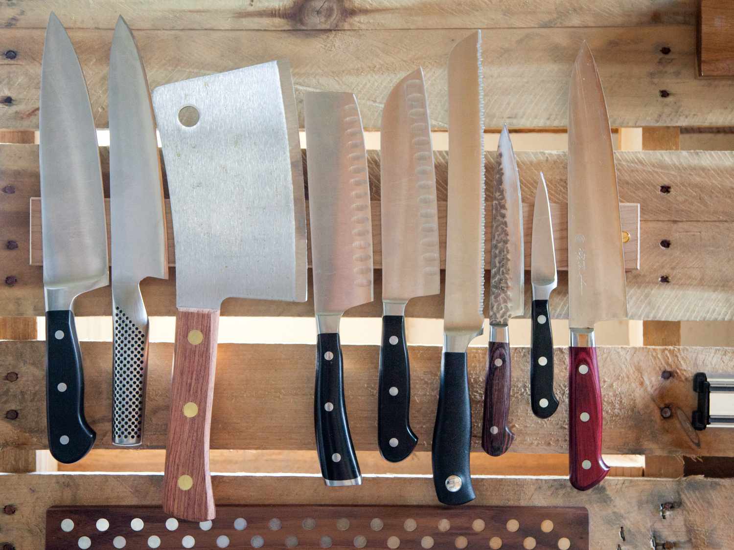 An assortment of knives on a wooden knife strip