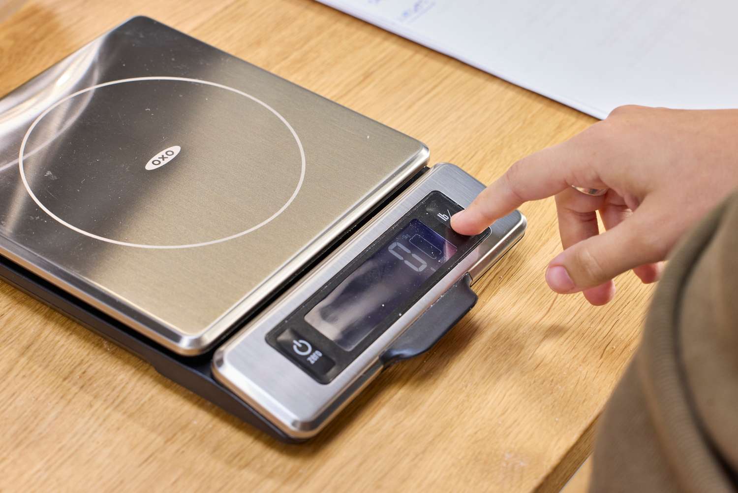 A person presses a button on the OXO Good Grips Stainless Steel Food Scale with Pull-Out Display