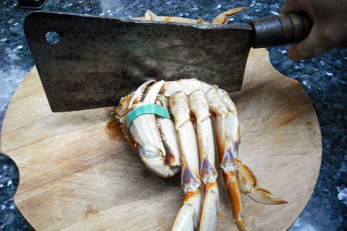 A large cleaver cutting down the center of a crab