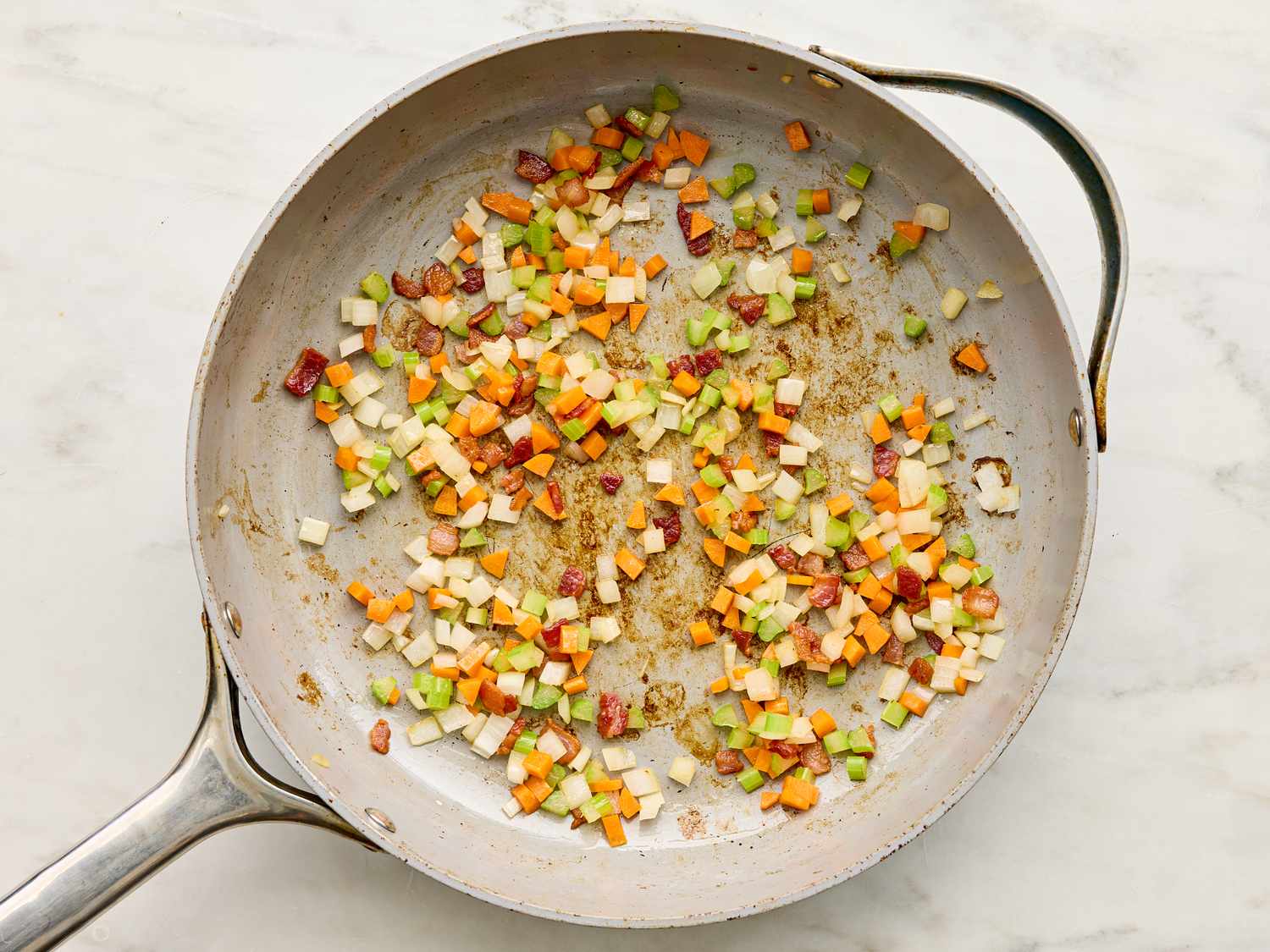 Diced vegetables sauting in a pan as part of a recipe step