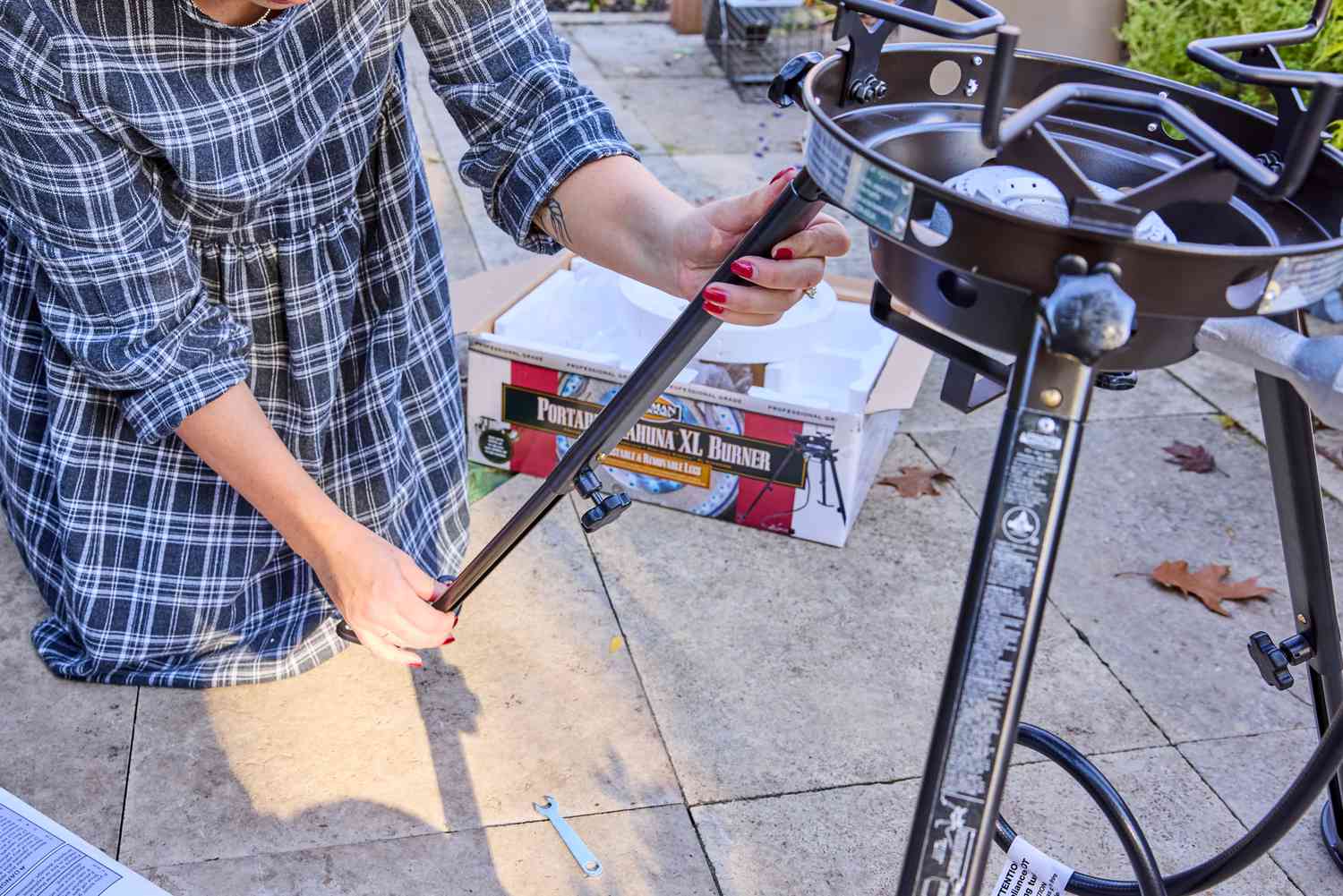 A person setting up the Eastman Outdoors wok burner on a patio.