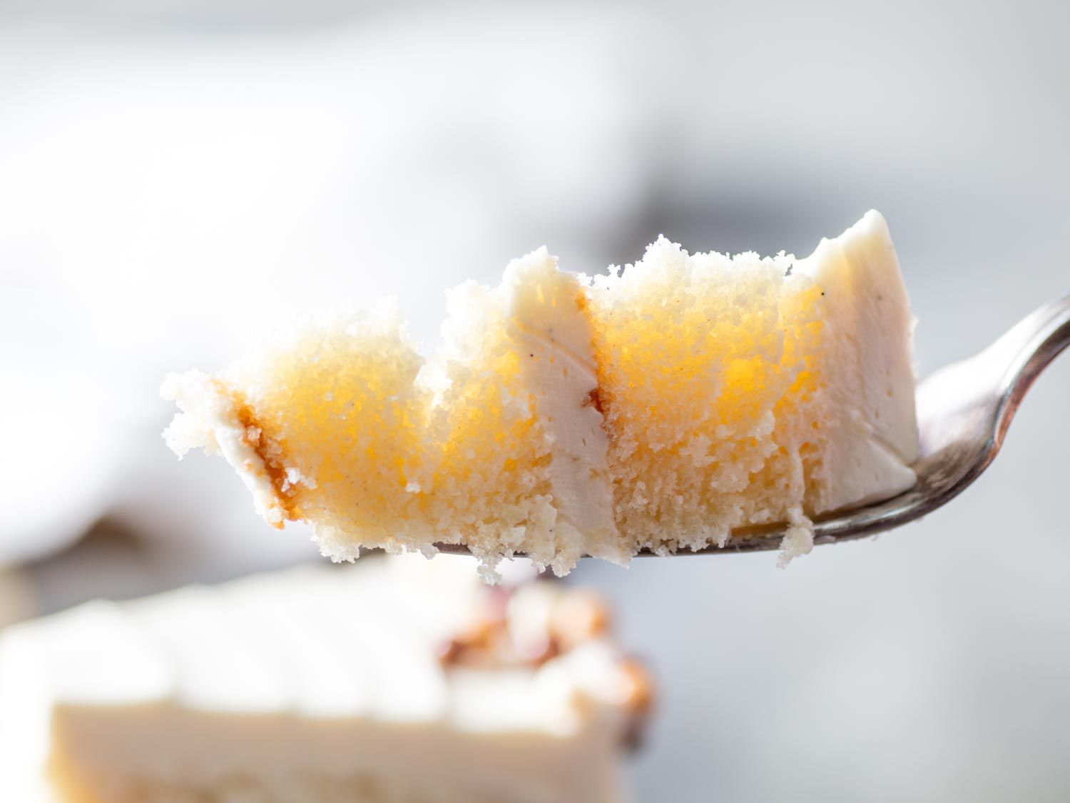 A fork holding a piece of vanilla butter cake. 